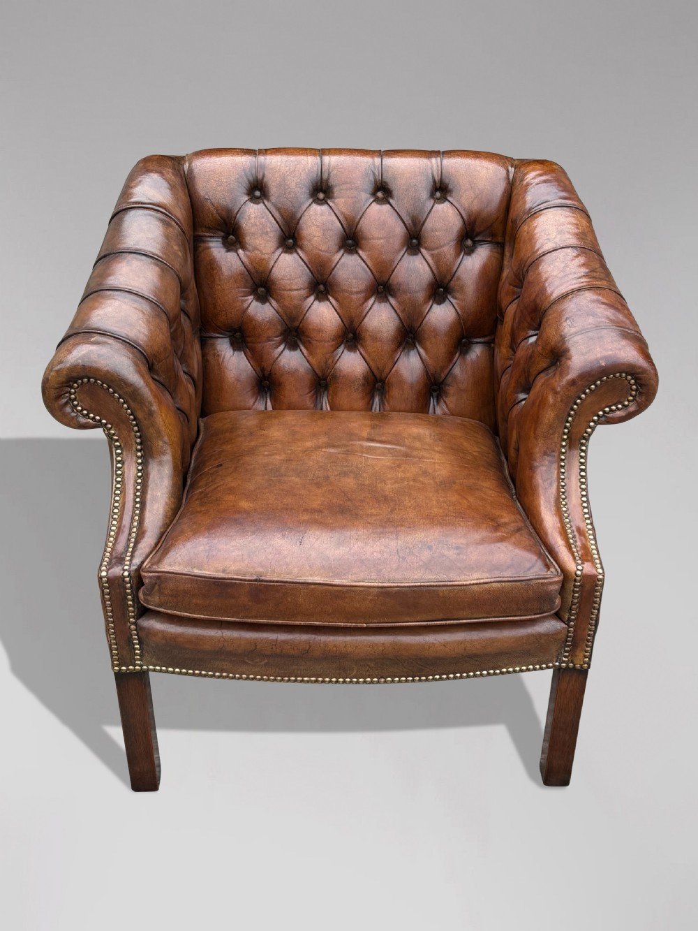 A 19th-century brown leather club armchair featuring deep button tufting, rolled arms with brass studding, and tapered timber legs. View II