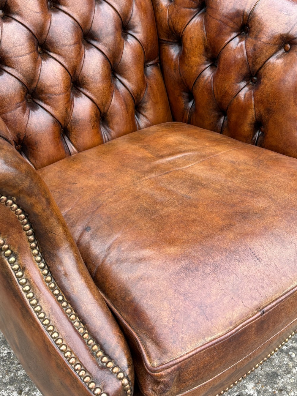 A 19th-century brown leather club armchair featuring deep button tufting, rolled arms with brass studding, and tapered timber legs. View IV