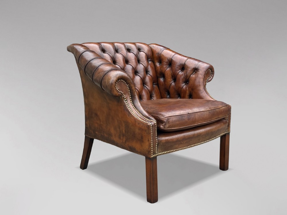 A 19th-century brown leather club armchair featuring deep button tufting, rolled arms with brass studding, and tapered timber legs. View VII