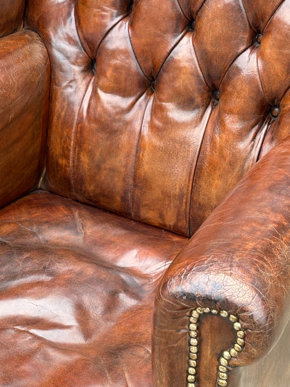 A 19th-century deep brown leather wingback armchair featuring a button-tufted backrest, brass stud trim, and hand-carved mahogany cabriole legs with ball-and-claw feet. View IV