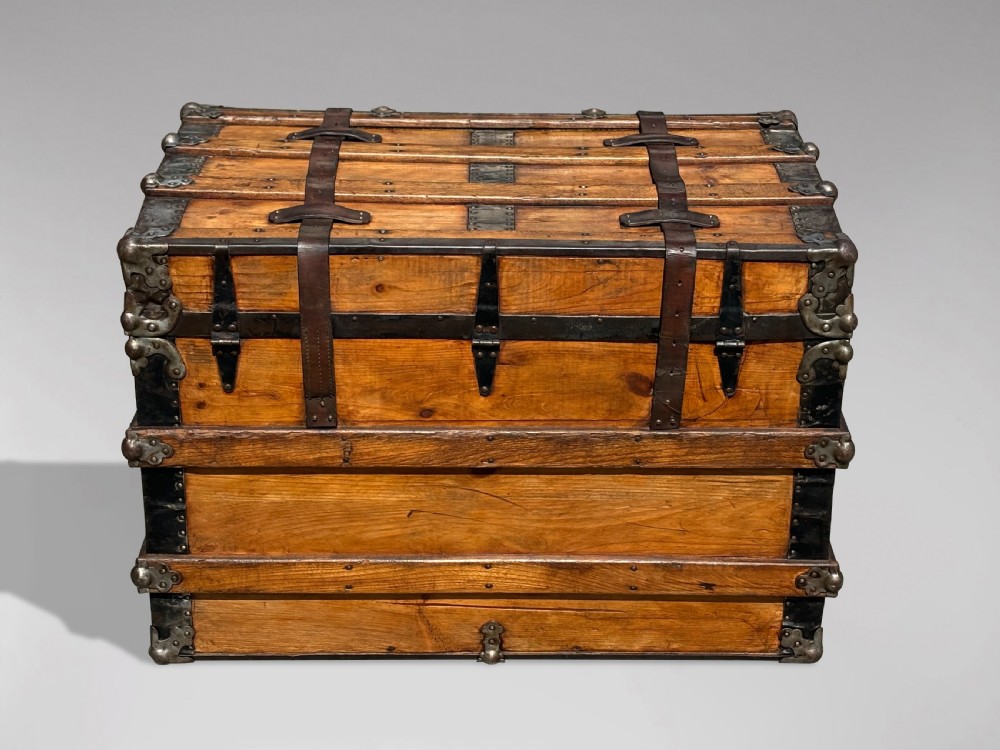 A 19th-century rectangular pine travelling trunk with metal corner protectors, horizontal wooden reinforcement slats, metal latches, and dual leather straps. View IV