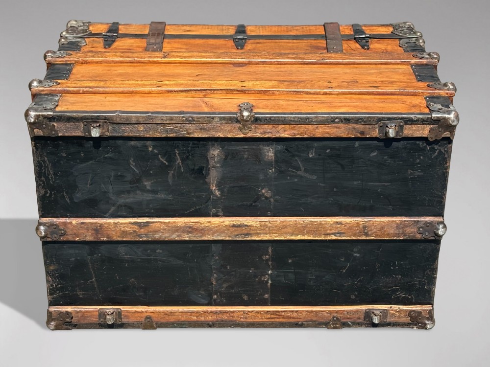 A 19th-century rectangular pine travelling trunk with metal corner protectors, horizontal wooden reinforcement slats, metal latches, and dual leather straps. View V