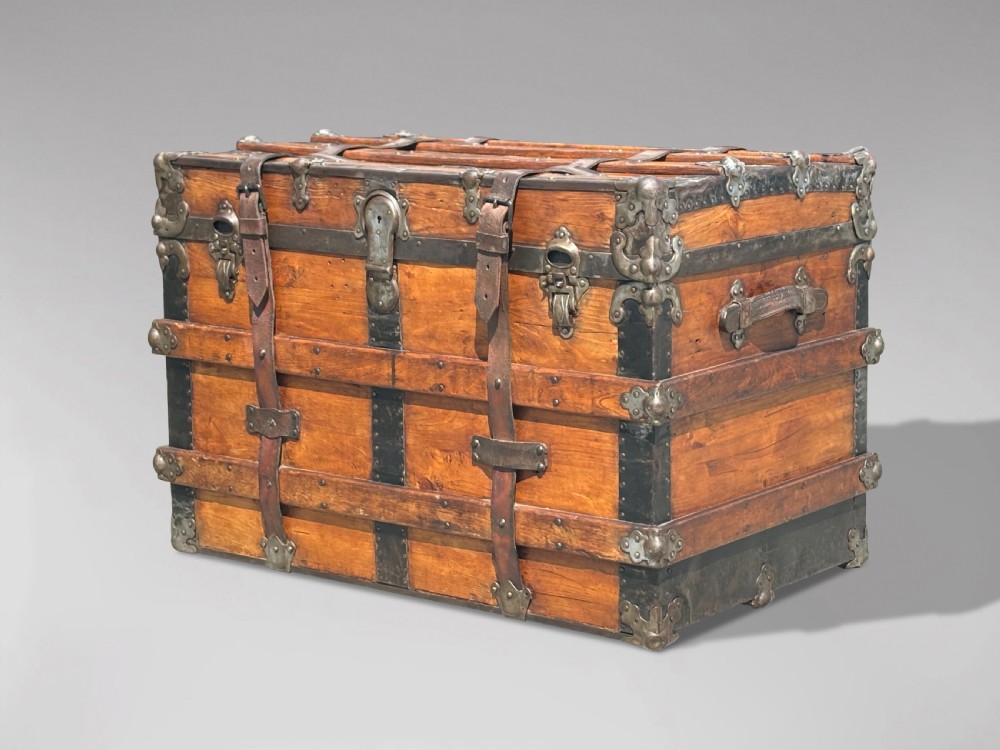 A 19th-century rectangular pine travelling trunk with metal corner protectors, horizontal wooden reinforcement slats, metal latches, and dual leather straps. View IX