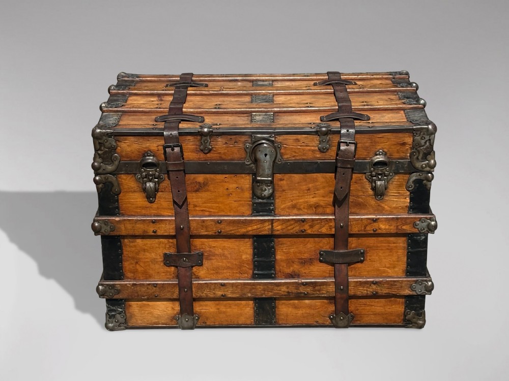 A 19th-century rectangular pine travelling trunk with metal corner protectors, horizontal wooden reinforcement slats, metal latches, and dual leather straps. View XI