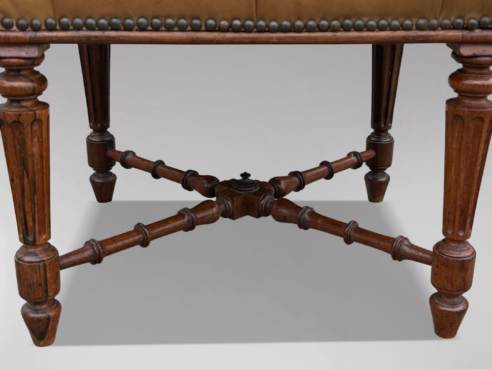 A 19th-century Regency period stool featuring a button-tufted tan leather seat with brass stud trimming, supported by turned fluted rosewood legs and turned stretchers. View IV