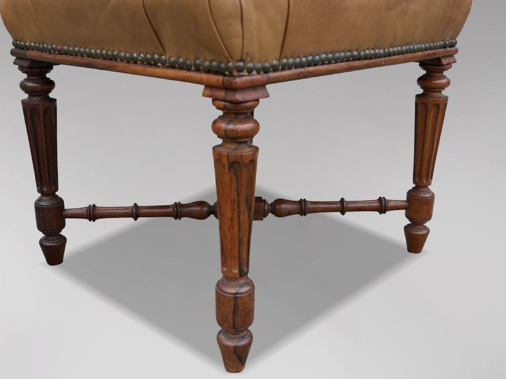 A 19th-century Regency period stool featuring a button-tufted tan leather seat with brass stud trimming, supported by turned fluted rosewood legs and turned stretchers. View V