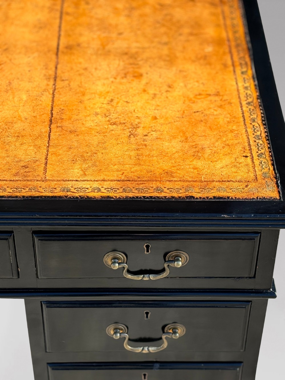 A 19th-century ebonised mahogany pedestal desk featuring a tan tooled leather inset top and brass swan-neck handles. View IV