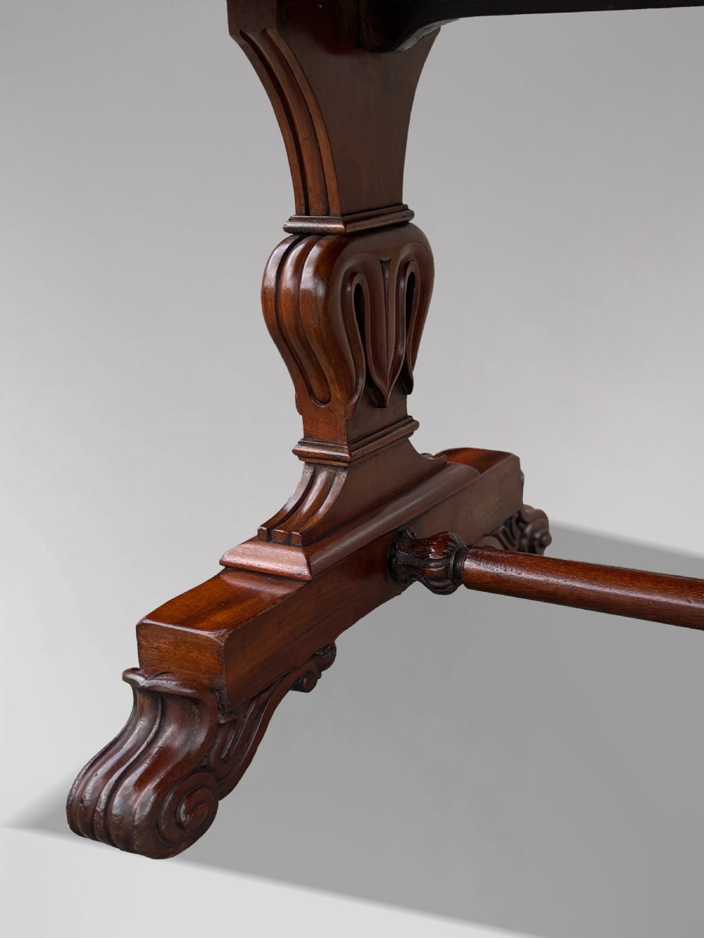 A 19th-century William IV mahogany writing table featuring a dark leather inset top, frieze drawers, carved trestle supports, and scroll feet. View IX