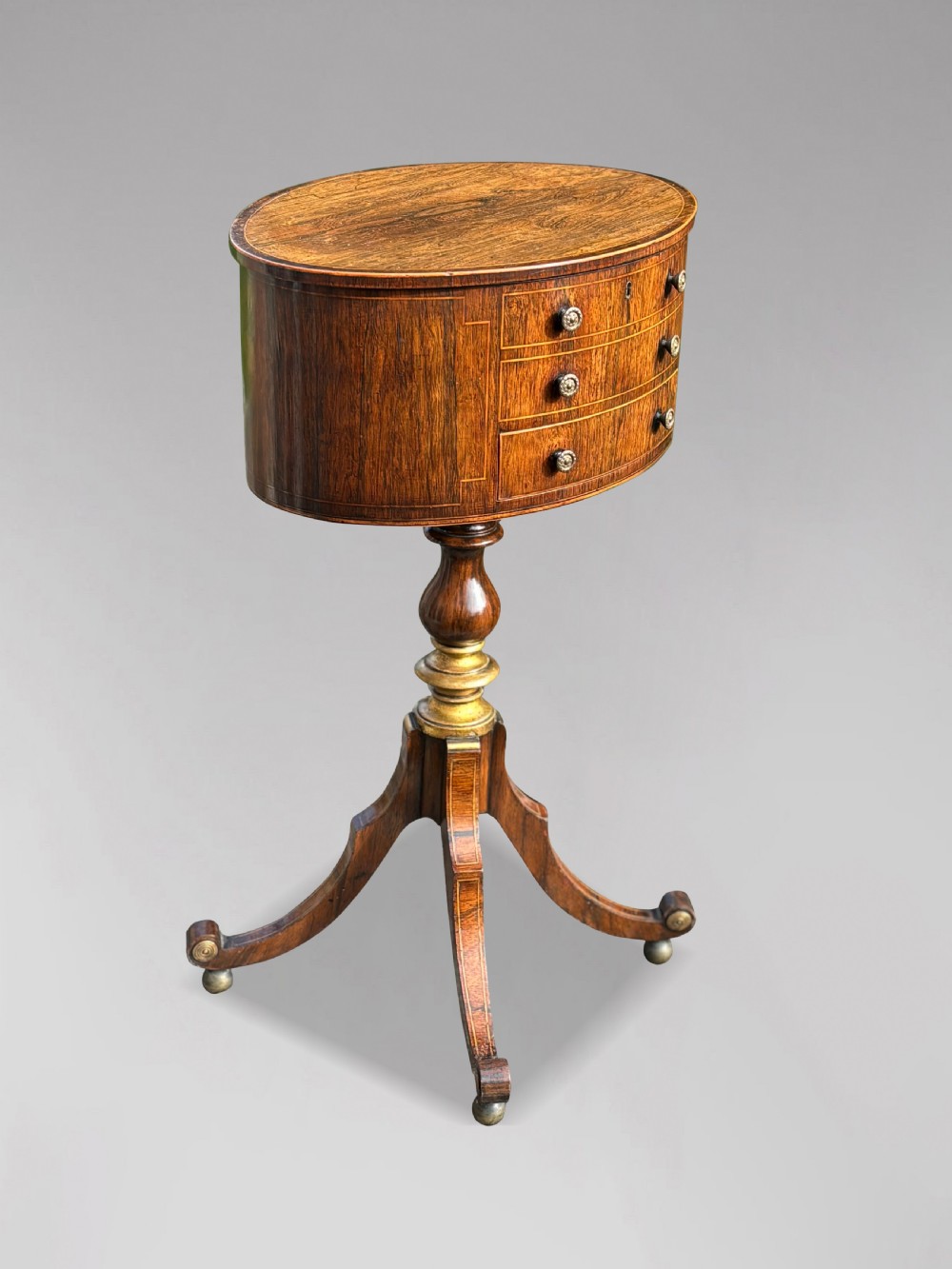 A 19th-century Regency rosewood circular work table featuring drawer fronts with brass knobs, a turned central stem, and a tripod base on ball feet. View IV