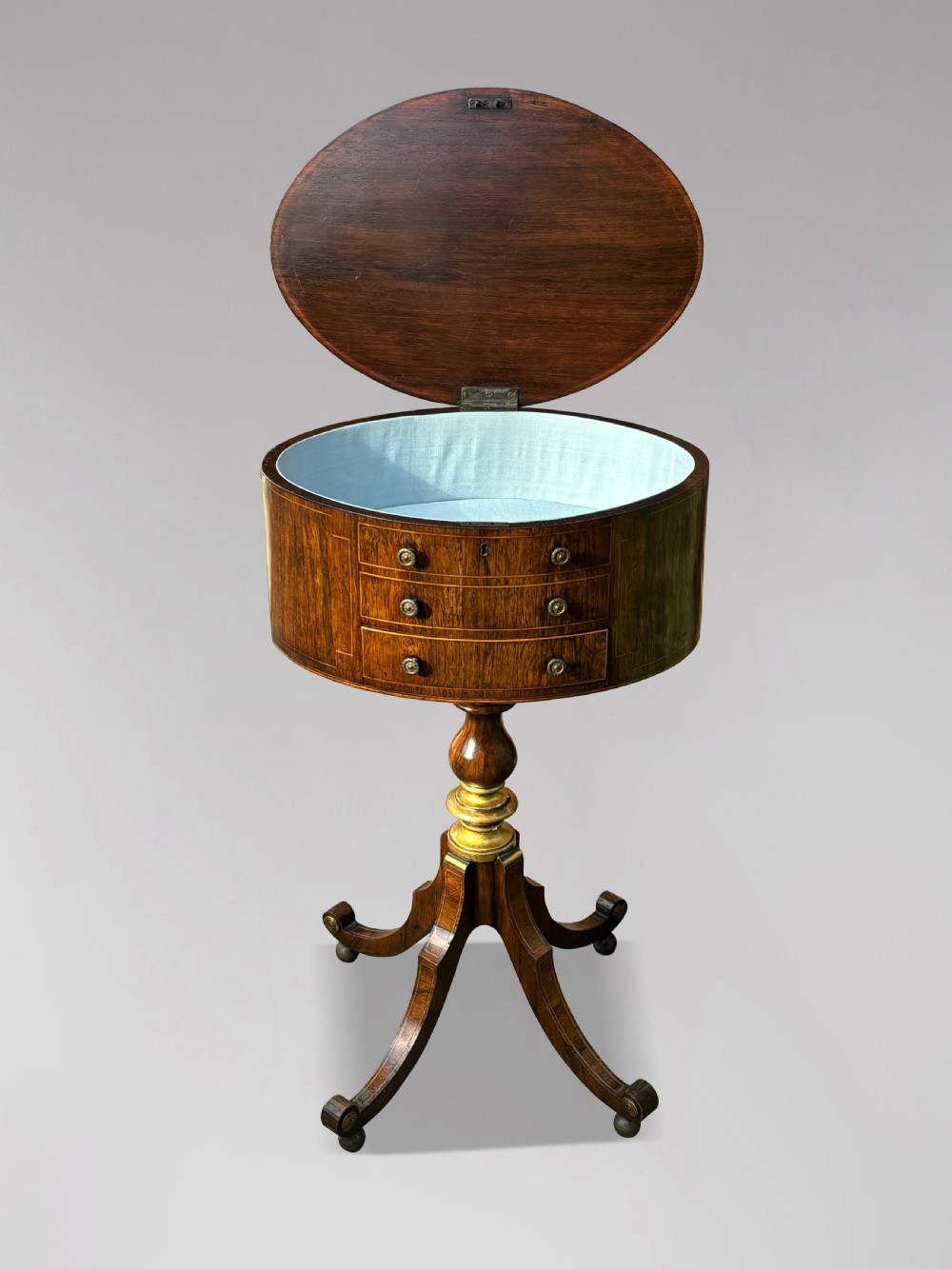 A 19th-century Regency rosewood circular work table featuring drawer fronts with brass knobs, a turned central stem, and a tripod base on ball feet. View V