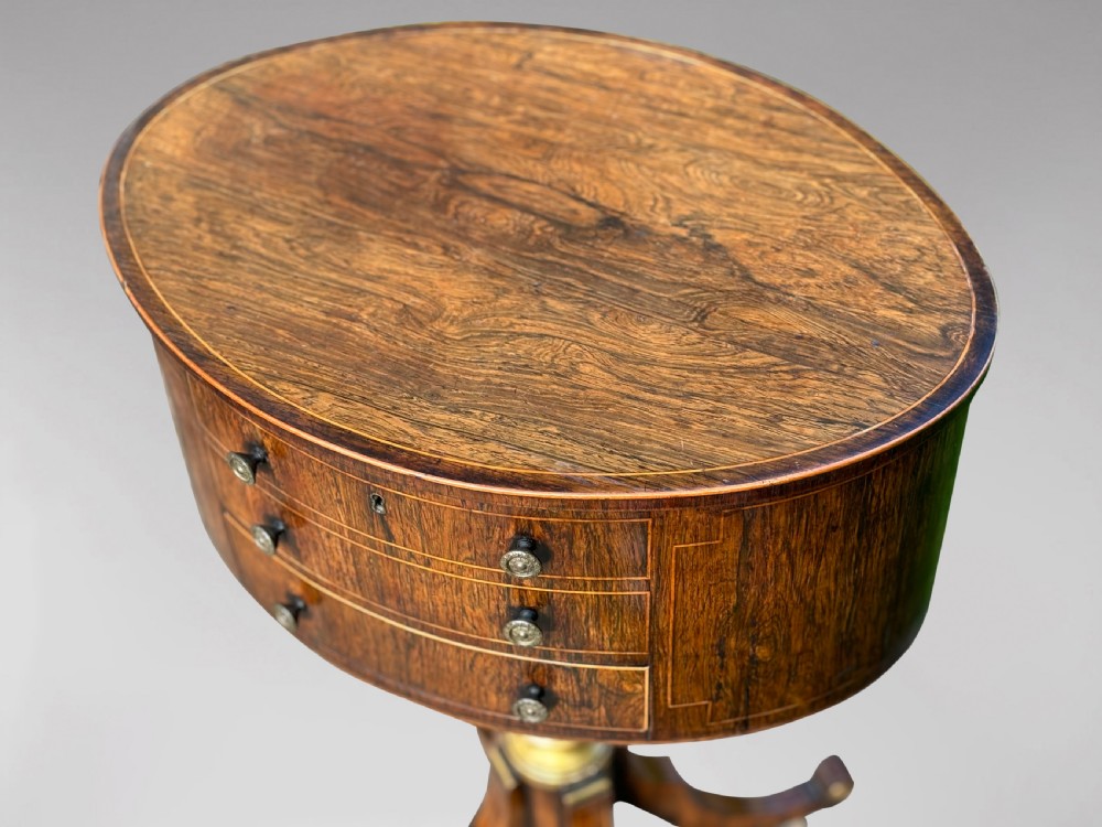 A 19th-century Regency rosewood circular work table featuring drawer fronts with brass knobs, a turned central stem, and a tripod base on ball feet. View VIII