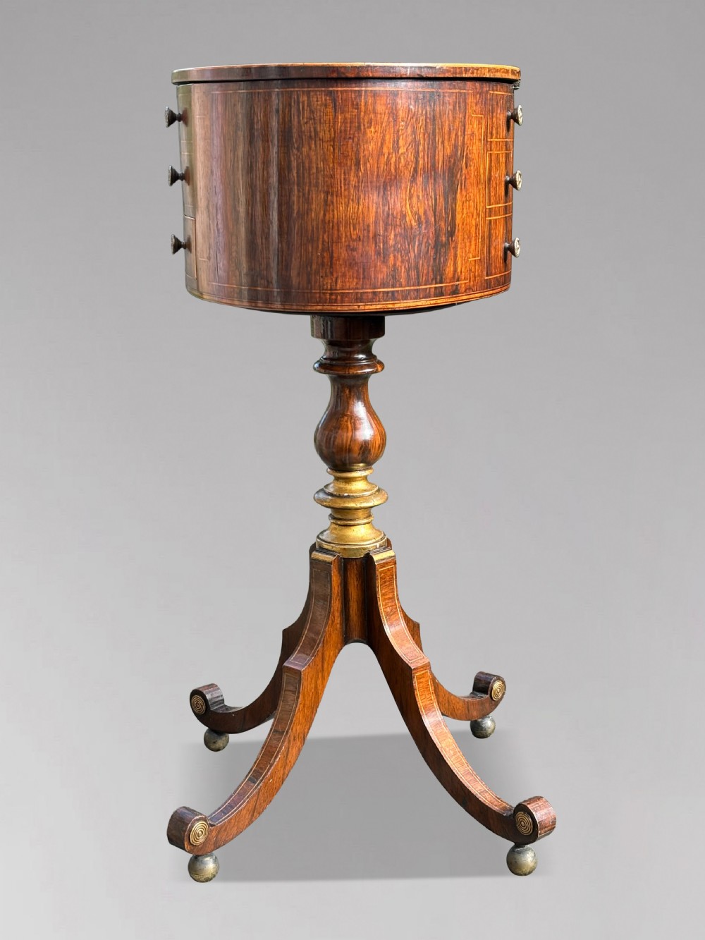 A 19th-century Regency rosewood circular work table featuring drawer fronts with brass knobs, a turned central stem, and a tripod base on ball feet. View IX