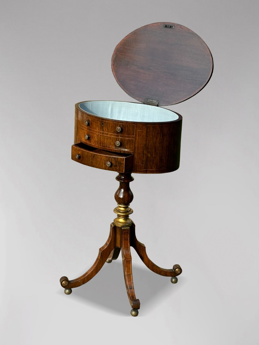 A 19th-century Regency rosewood circular work table featuring drawer fronts with brass knobs, a turned central stem, and a tripod base on ball feet. View XII