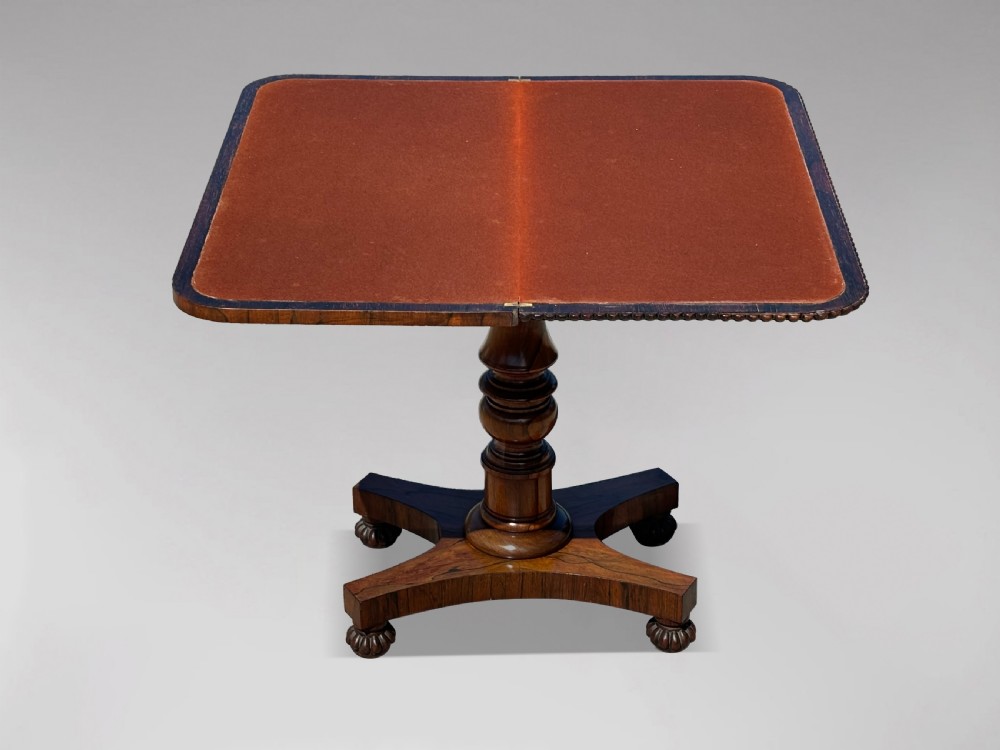 A 19th-century William IV rosewood fold-over card table featuring a gadrooned rim, a turned column stem, and a concave platform base with carved feet. View IV