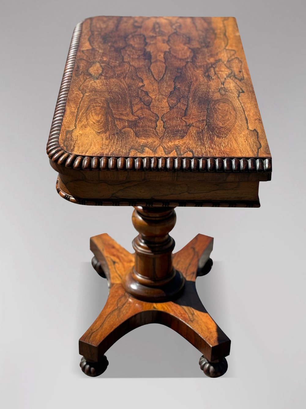 A 19th-century William IV rosewood fold-over card table featuring a gadrooned rim, a turned column stem, and a concave platform base with carved feet. View V
