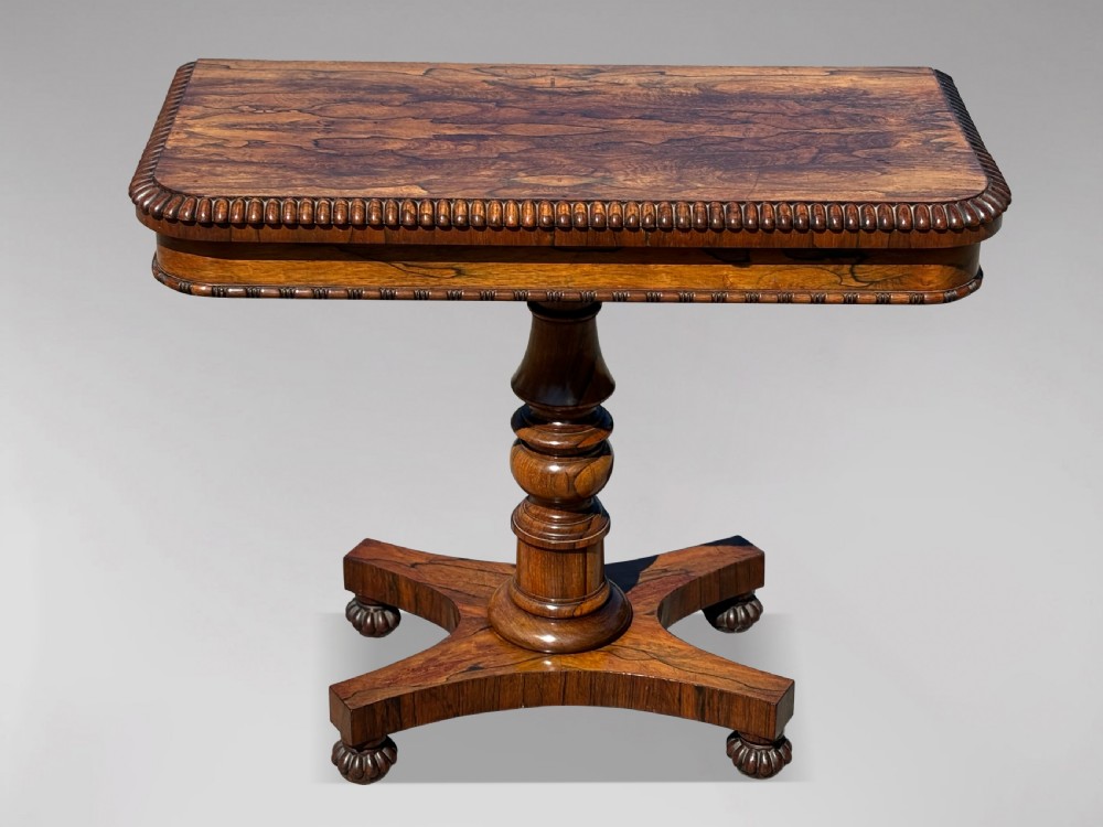 A 19th-century William IV rosewood fold-over card table featuring a gadrooned rim, a turned column stem, and a concave platform base with carved feet. View VIII