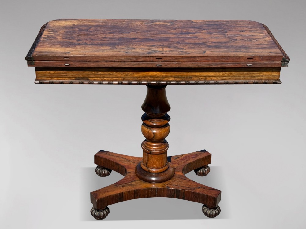 A 19th-century William IV rosewood fold-over card table featuring a gadrooned rim, a turned column stem, and a concave platform base with carved feet. View IX