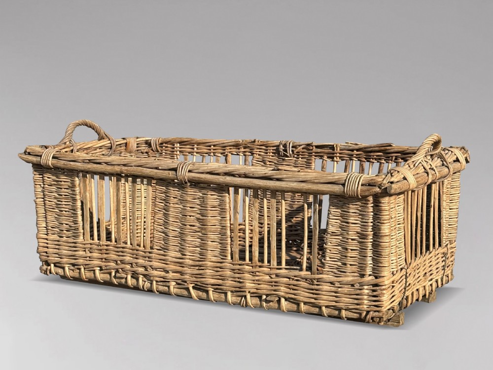 A large rectangular French wicker basket featuring open vertical weave, woven loop handles, and wooden runner skids along the base. View II