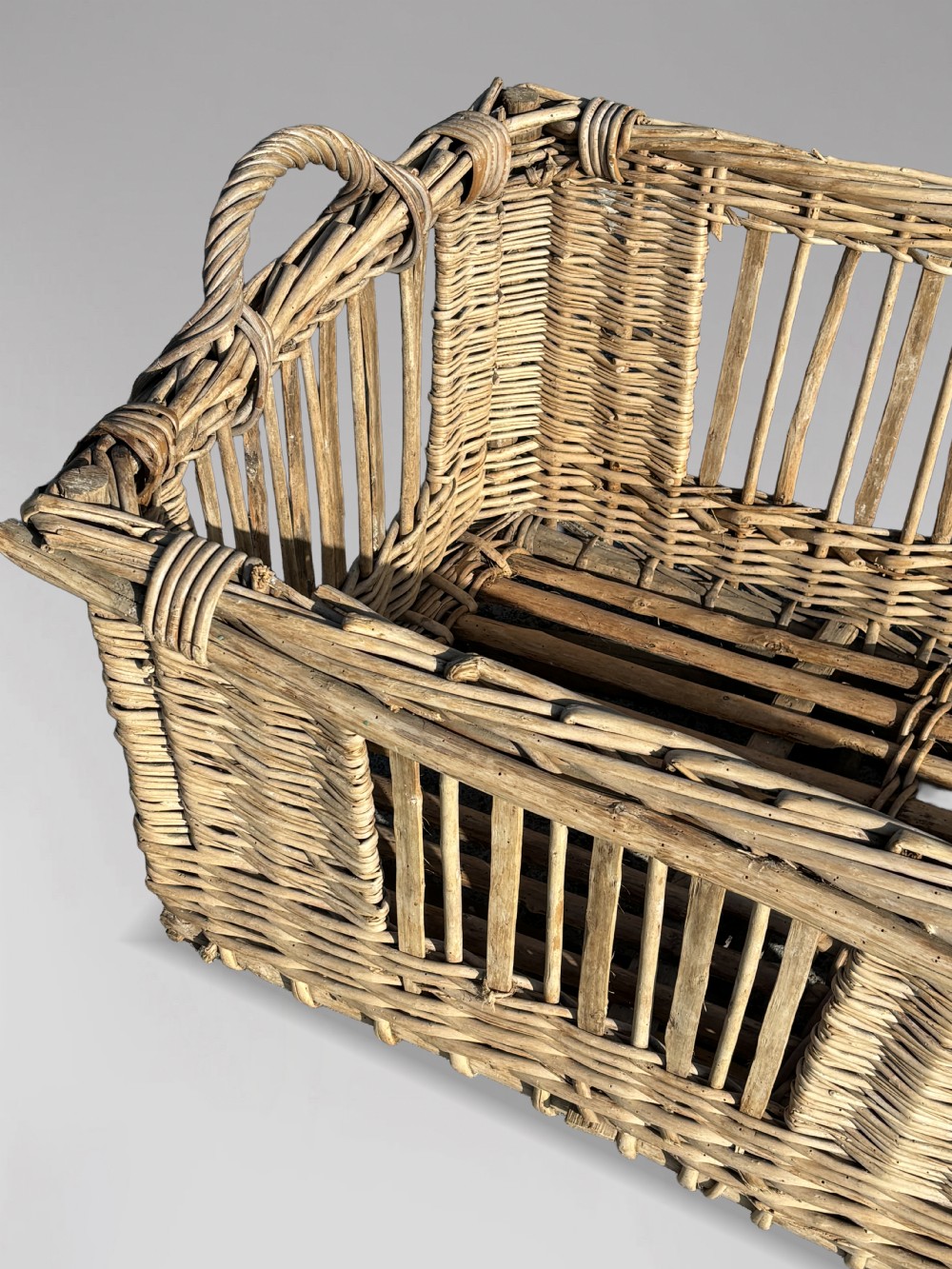 A large rectangular French wicker basket featuring open vertical weave, woven loop handles, and wooden runner skids along the base. View III