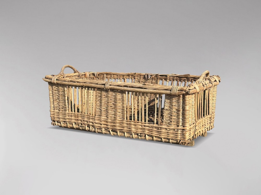 A large rectangular French wicker basket featuring open vertical weave, woven loop handles, and wooden runner skids along the base. View VII