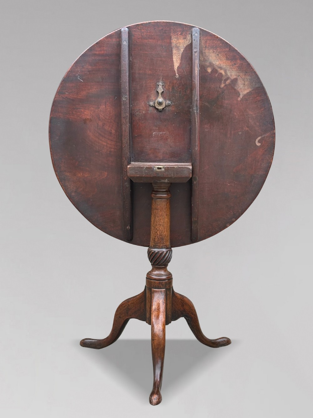 An 18th-century George III mahogany tripod table with its circular top tilted vertically above a turned central column and three cabriole legs. View II