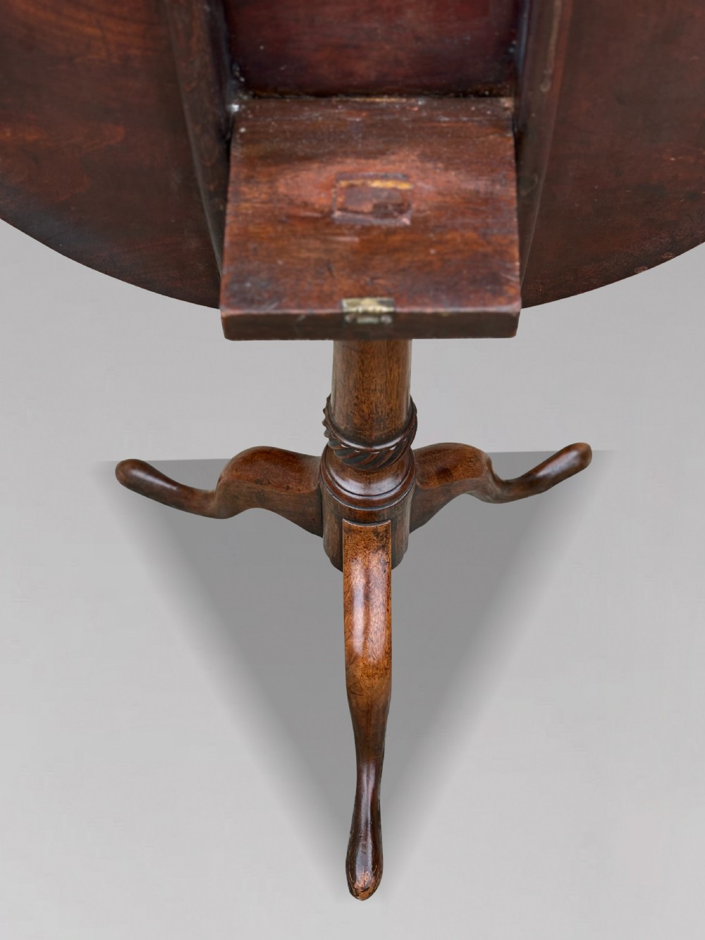 An 18th-century George III mahogany tripod table with its circular top tilted vertically above a turned central column and three cabriole legs. View III
