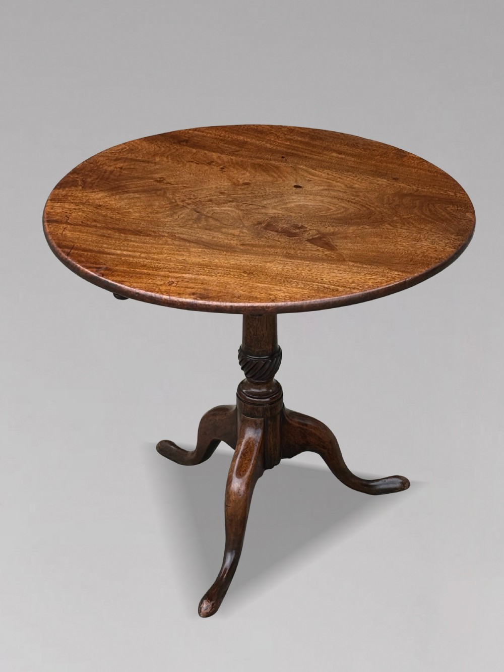 An 18th-century George III mahogany tripod table with its circular top tilted vertically above a turned central column and three cabriole legs. View IV