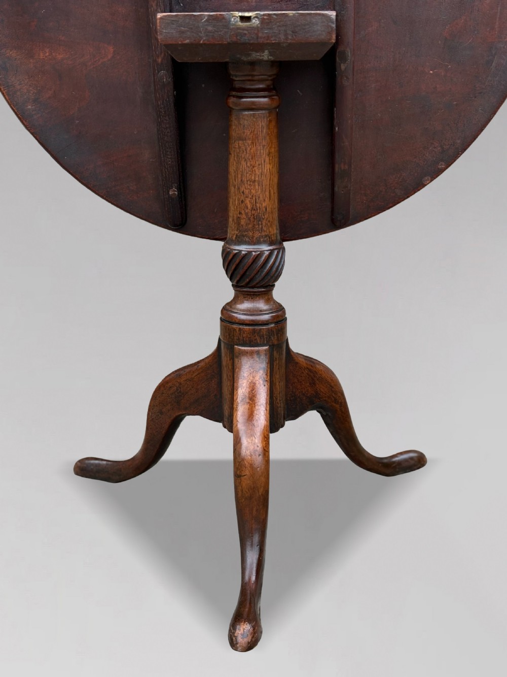 An 18th-century George III mahogany tripod table with its circular top tilted vertically above a turned central column and three cabriole legs. View VII