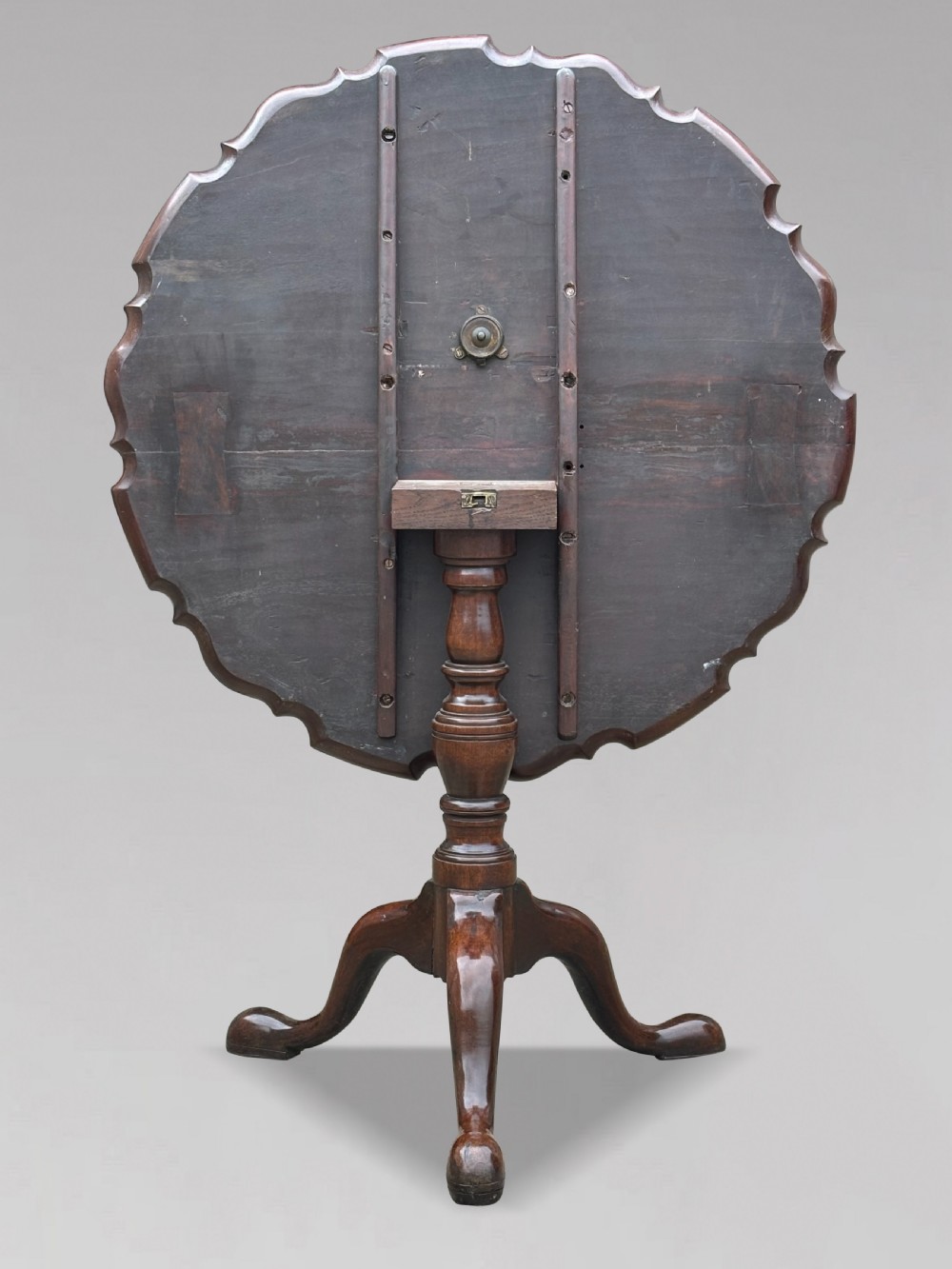 An 18th-century George III mahogany tilt-top tripod table shown in the vertical position with a carved pie-crust rim, turned pedestal, and cabriole legs. View II
