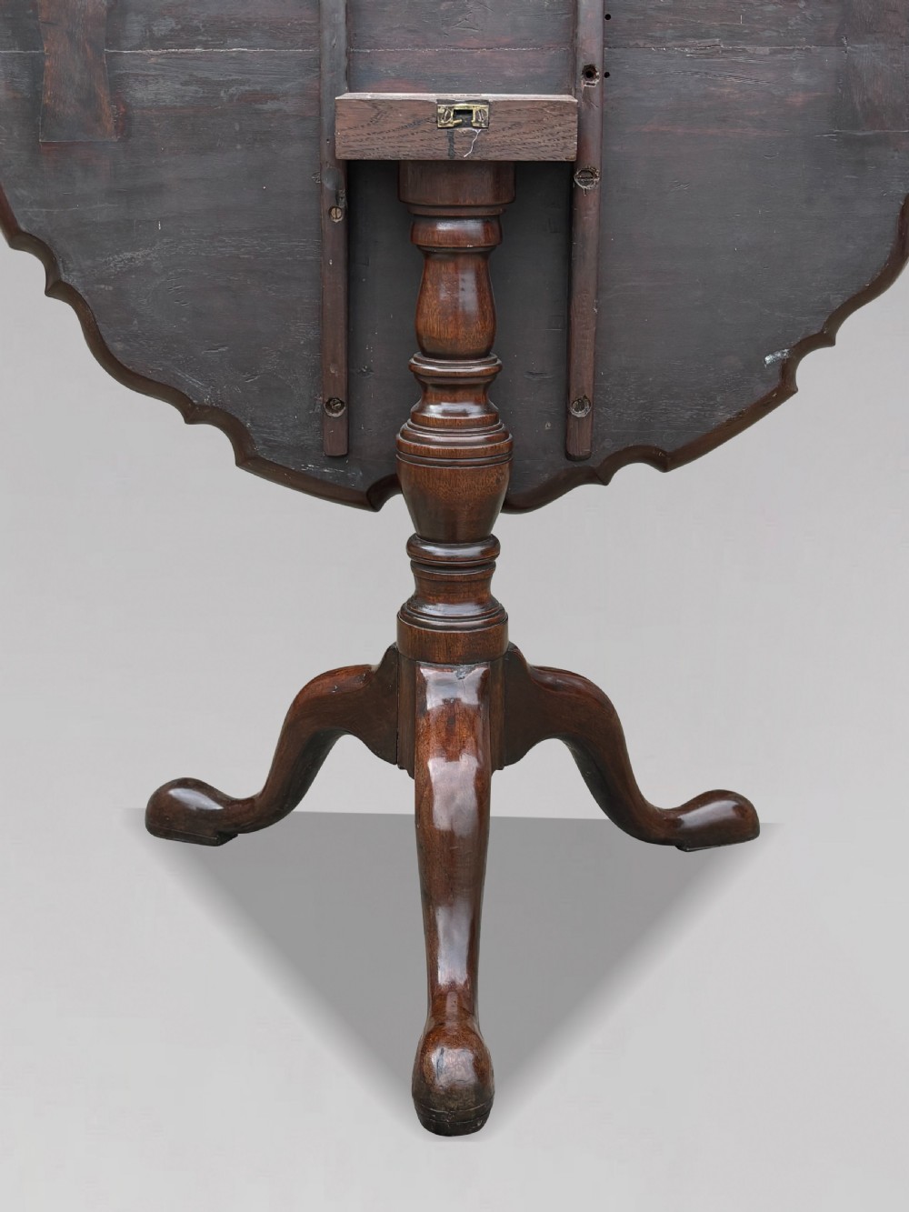 An 18th-century George III mahogany tilt-top tripod table shown in the vertical position with a carved pie-crust rim, turned pedestal, and cabriole legs. View VII