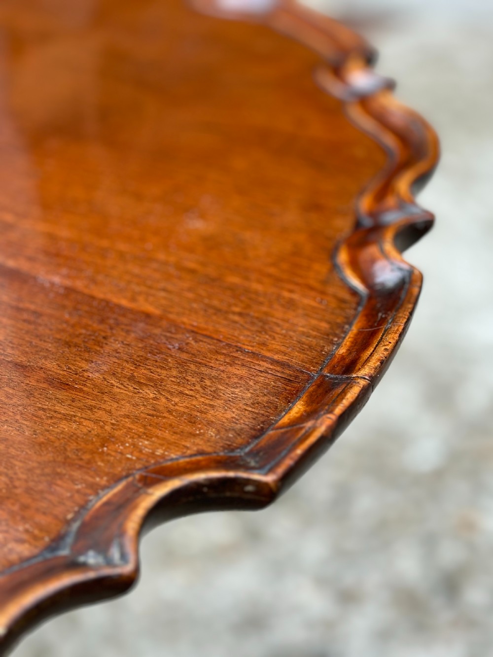 An 18th-century George III mahogany tilt-top tripod table shown in the vertical position with a carved pie-crust rim, turned pedestal, and cabriole legs. View IX