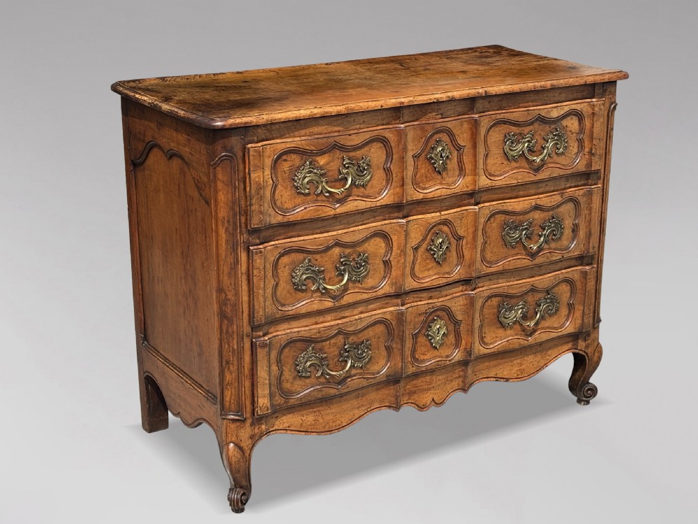 An eighteenth-century French Louis XV walnut commode featuring three carved drawers with rococo brass handles and cabriole legs. View II