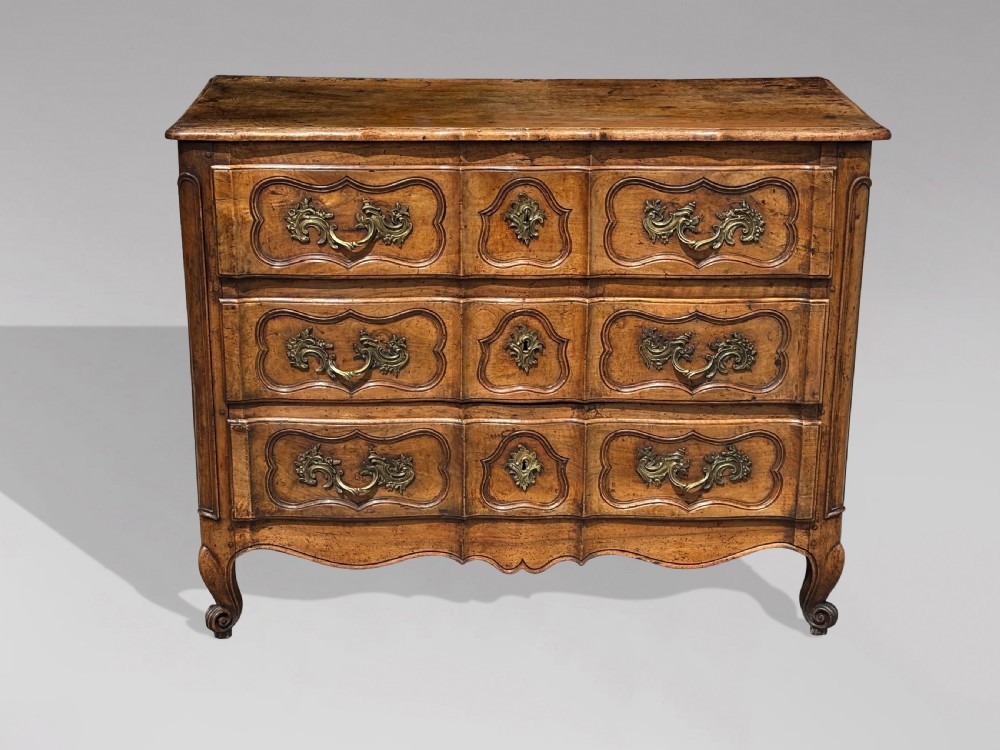 An eighteenth-century French Louis XV walnut commode featuring three carved drawers with rococo brass handles and cabriole legs. View V