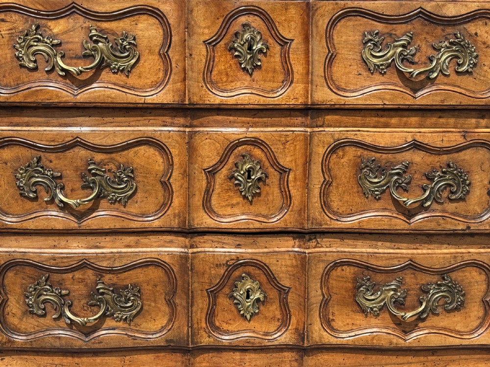 An eighteenth-century French Louis XV walnut commode featuring three carved drawers with rococo brass handles and cabriole legs. View VI