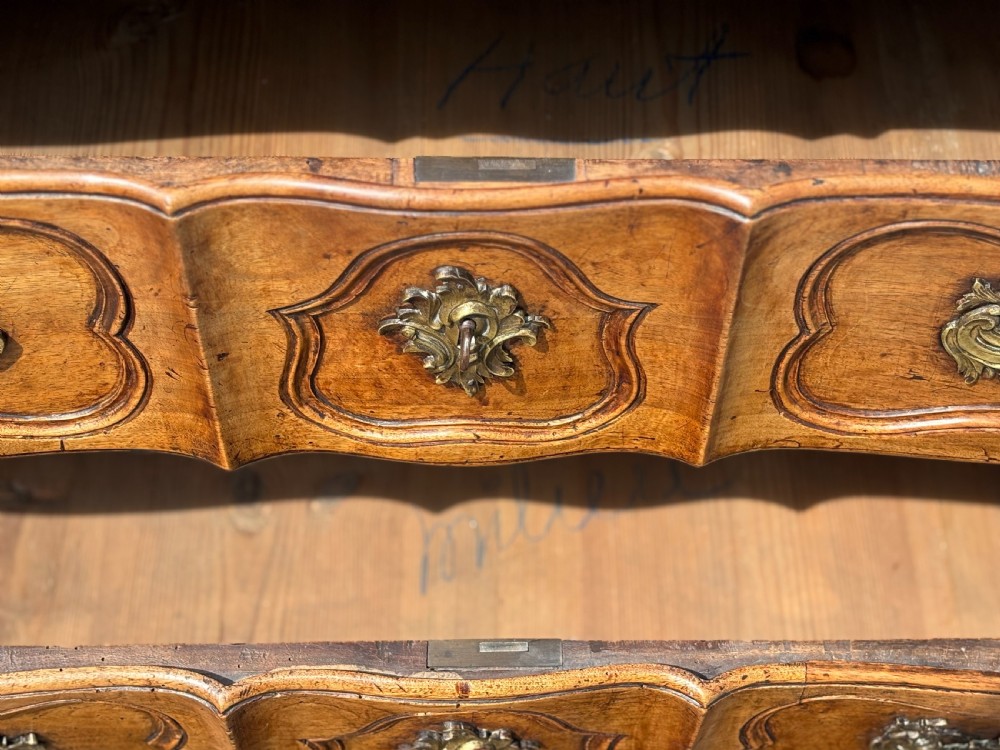 An eighteenth-century French Louis XV walnut commode featuring three carved drawers with rococo brass handles and cabriole legs. View VII