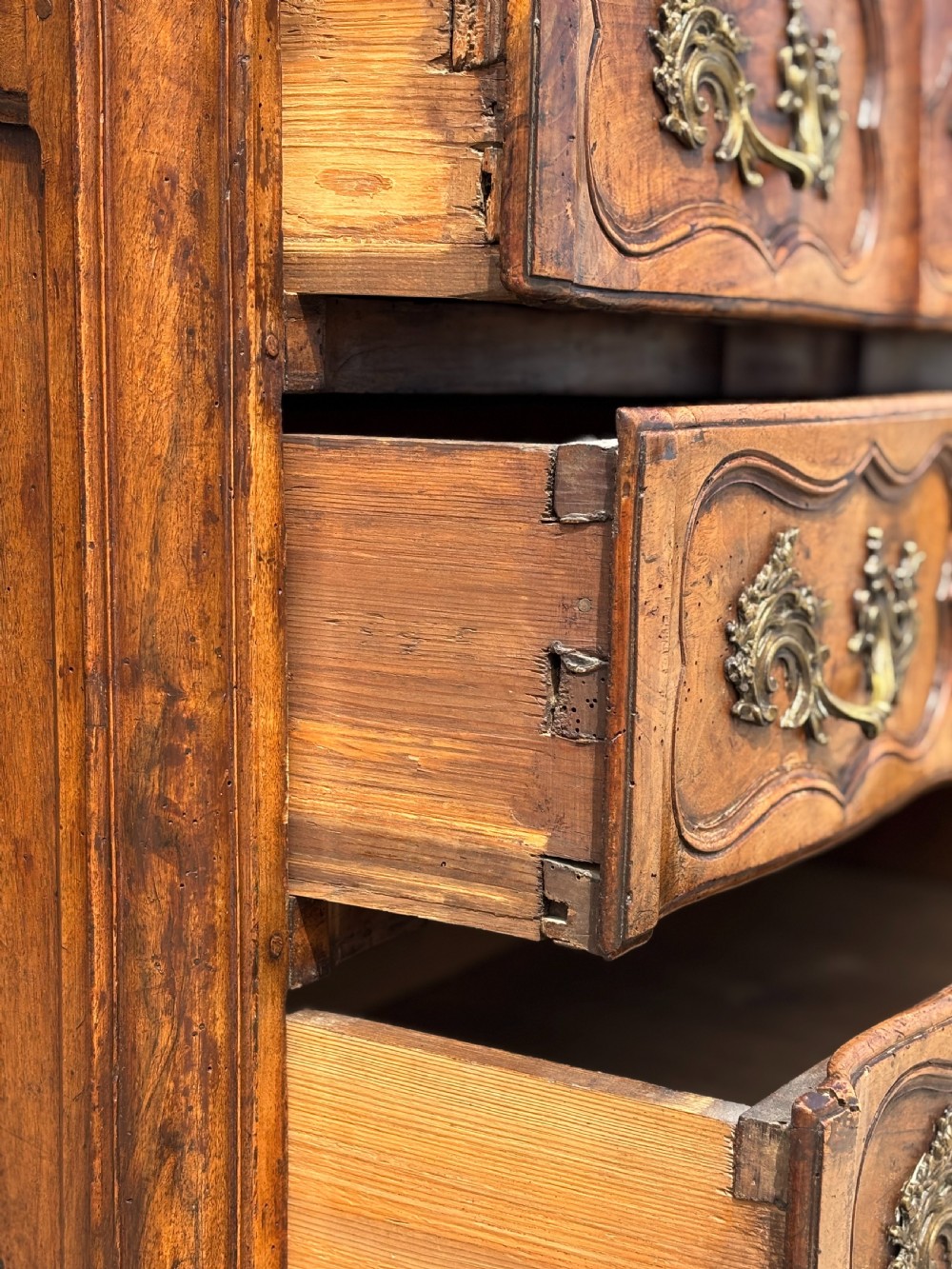An eighteenth-century French Louis XV walnut commode featuring three carved drawers with rococo brass handles and cabriole legs. View VIII