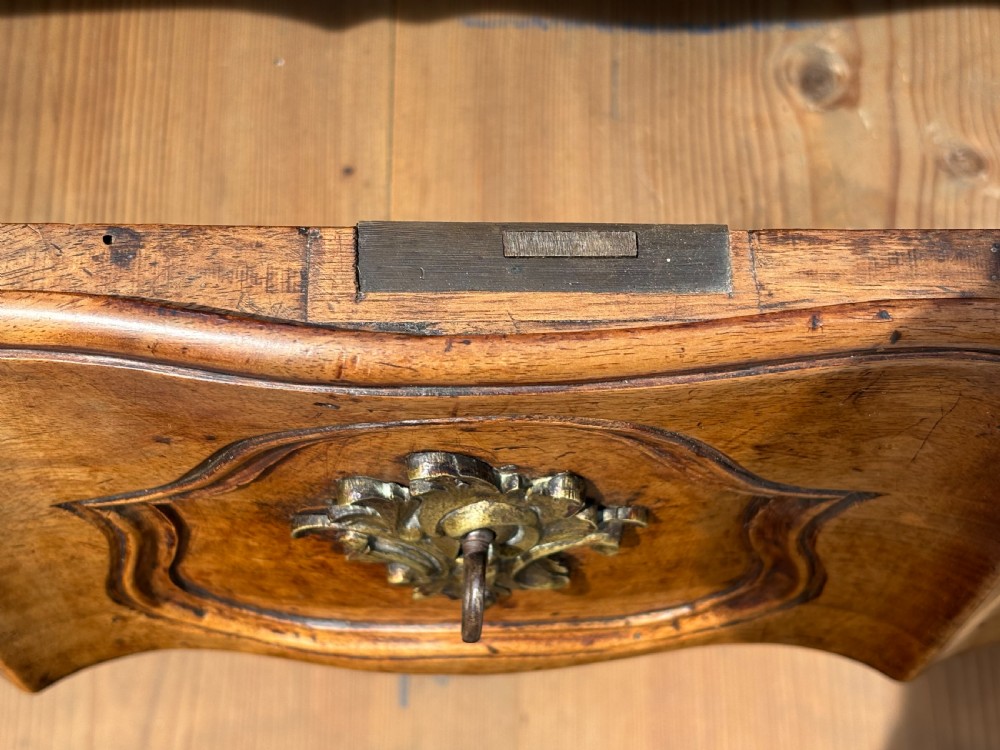 An eighteenth-century French Louis XV walnut commode featuring three carved drawers with rococo brass handles and cabriole legs. View X