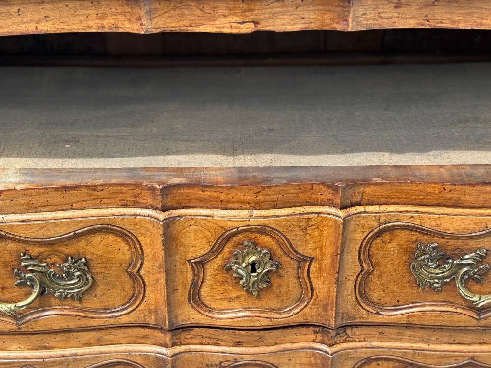 An eighteenth-century French Louis XV walnut commode featuring three carved drawers with rococo brass handles and cabriole legs. View XI
