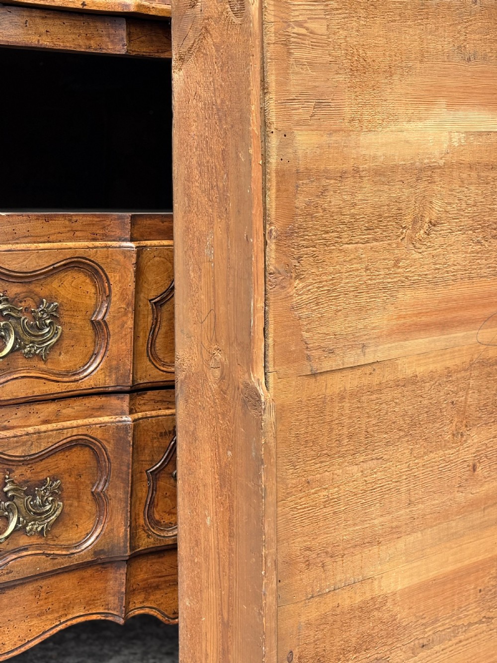 An eighteenth-century French Louis XV walnut commode featuring three carved drawers with rococo brass handles and cabriole legs. View XII