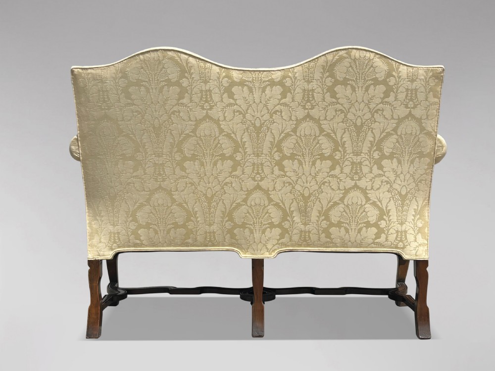 An Edwardian Queen Anne style settee upholstered in cream damask with carved walnut cabriole legs and a double-arched back. View III