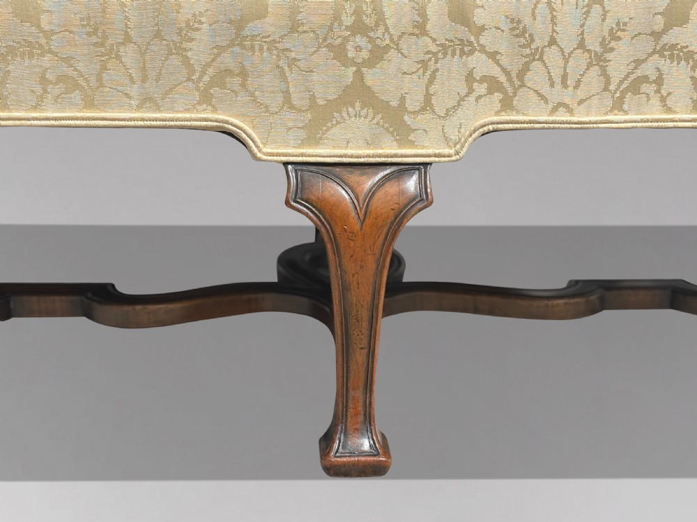An Edwardian Queen Anne style settee upholstered in cream damask with carved walnut cabriole legs and a double-arched back. View V