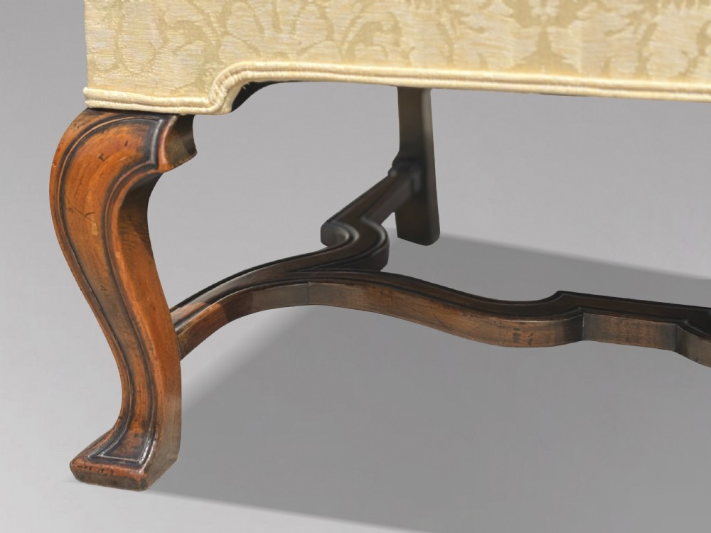 An Edwardian Queen Anne style settee upholstered in cream damask with carved walnut cabriole legs and a double-arched back. View VI
