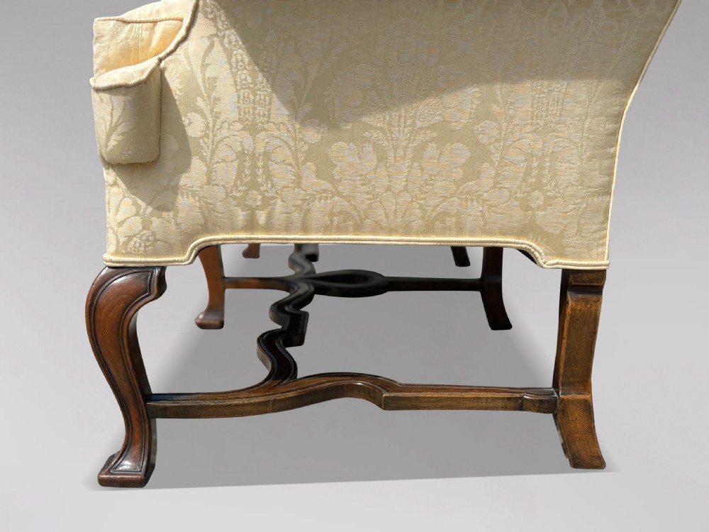 An Edwardian Queen Anne style settee upholstered in cream damask with carved walnut cabriole legs and a double-arched back. View VII