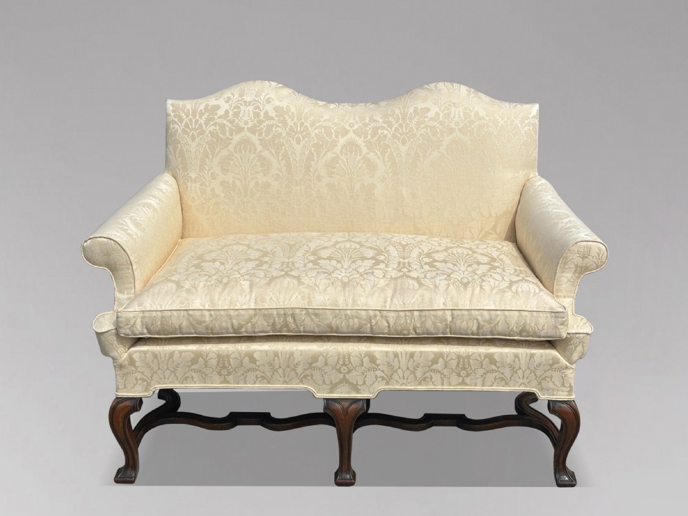 An Edwardian Queen Anne style settee upholstered in cream damask with carved walnut cabriole legs and a double-arched back. View X