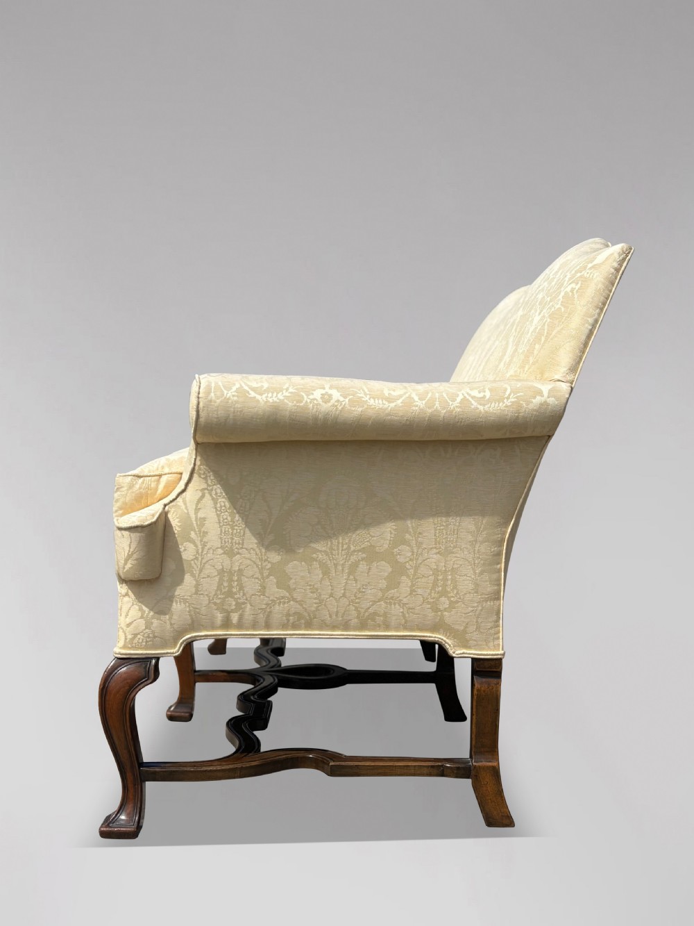 An Edwardian Queen Anne style settee upholstered in cream damask with carved walnut cabriole legs and a double-arched back. View XI