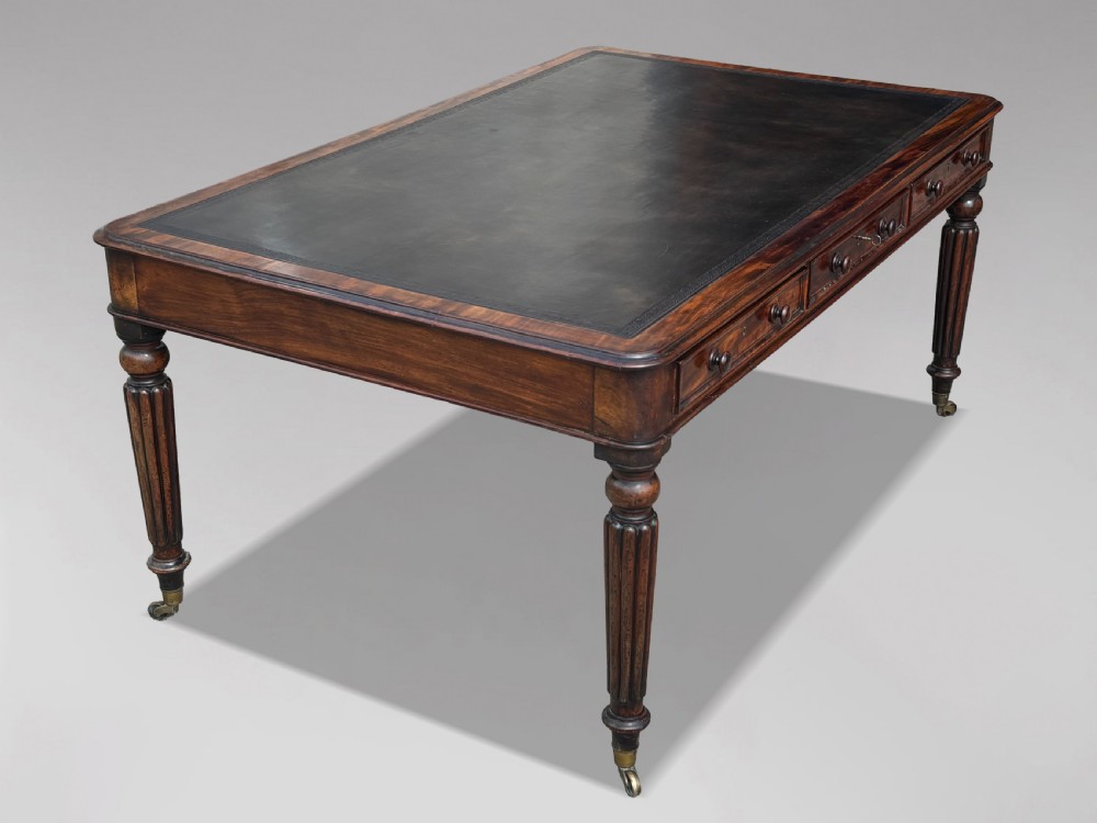 An 18th-century mahogany library table featuring a black leather top insert, frieze drawers with wooden knob handles, and turned, fluted legs on brass castors. View III