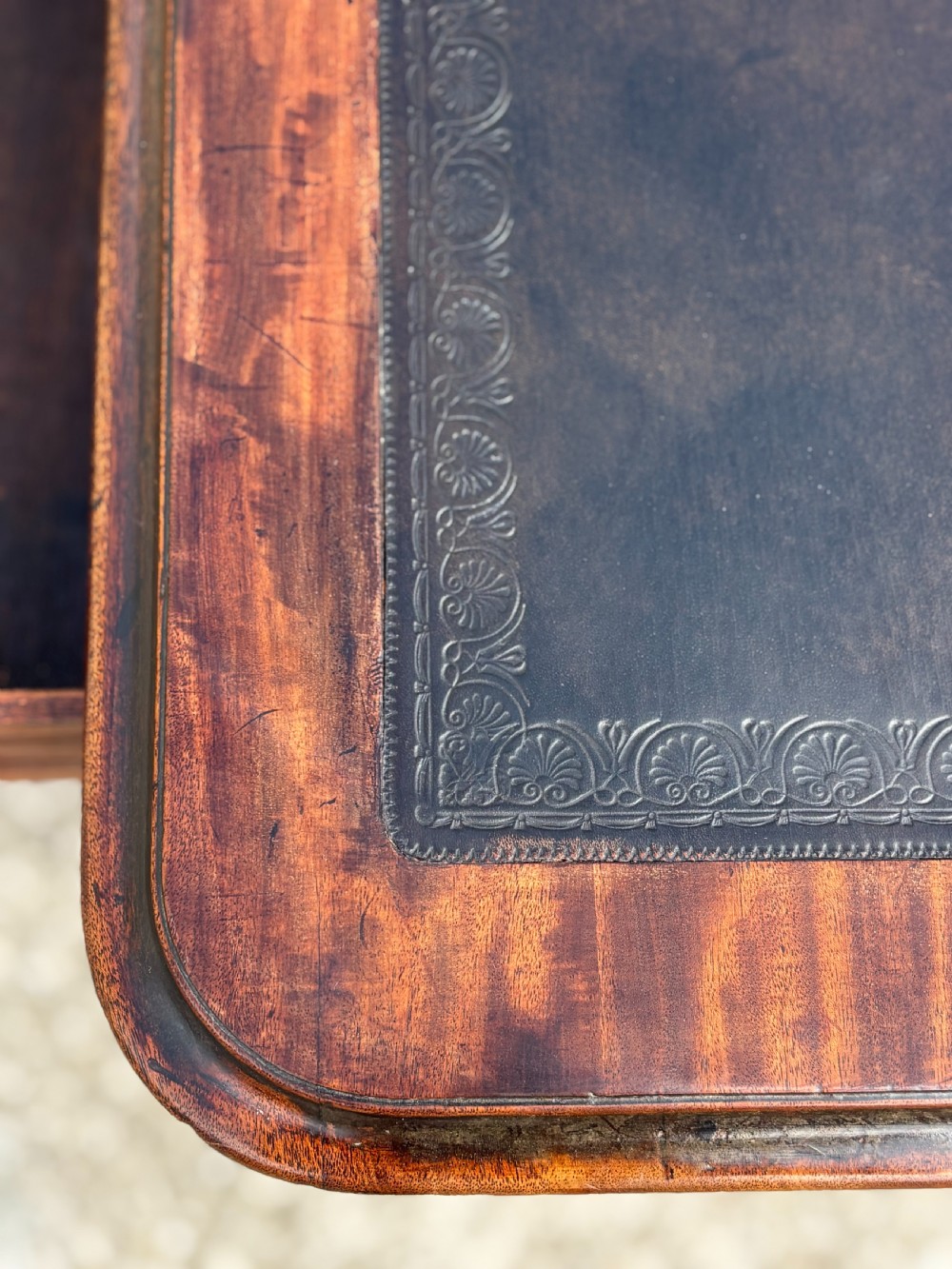 An 18th-century mahogany library table featuring a black leather top insert, frieze drawers with wooden knob handles, and turned, fluted legs on brass castors. View X