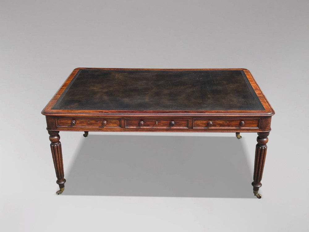 An 18th-century mahogany library table featuring a black leather top insert, frieze drawers with wooden knob handles, and turned, fluted legs on brass castors. View XIII