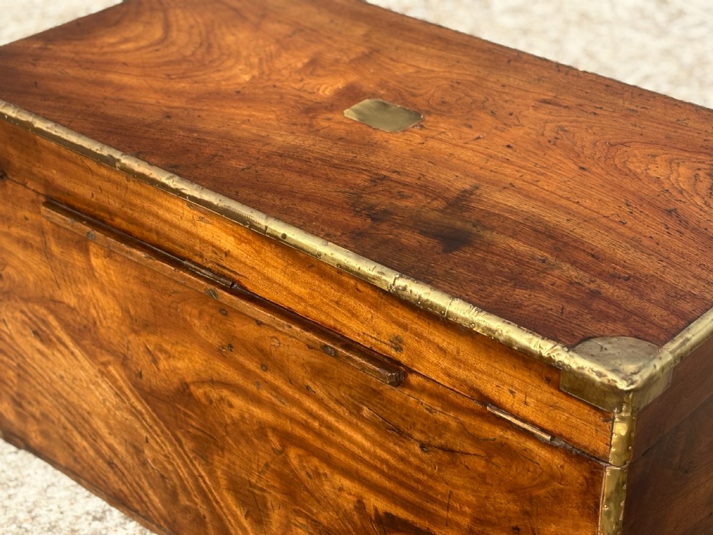 A rectangular 19th-century camphor wood campaign trunk with brass corner strapping, edge binding, a central flush plaque, and iron side handles. View VI