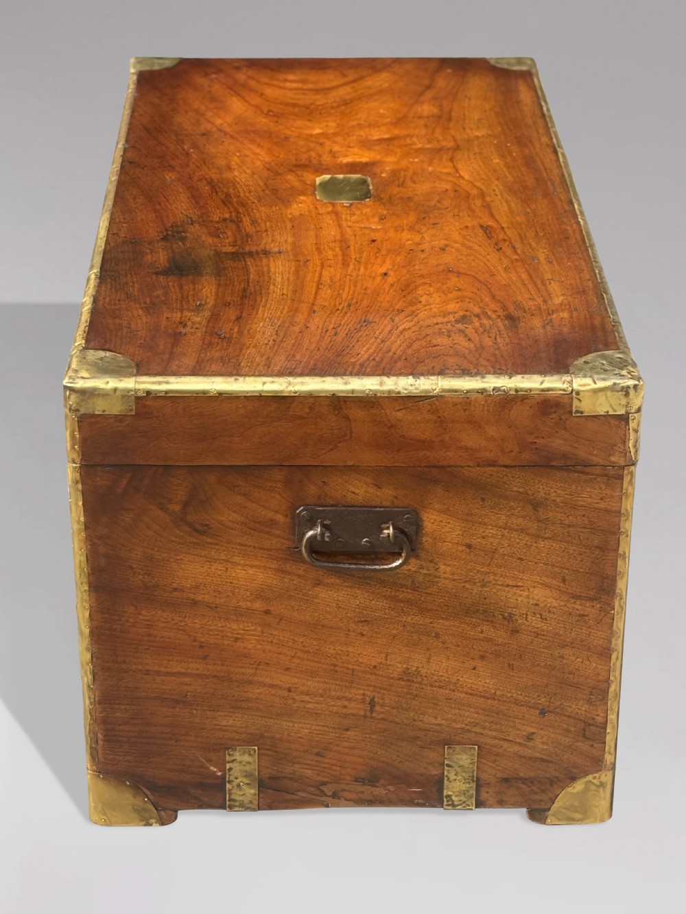 A rectangular 19th-century camphor wood campaign trunk with brass corner strapping, edge binding, a central flush plaque, and iron side handles. View IX